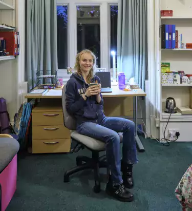 Student with mug of tea in room